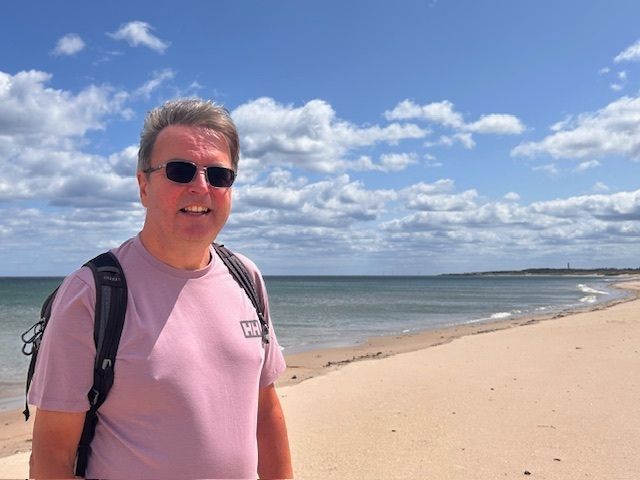 Ceri in sunglasses and a pink t-shirt, at the beach in Northumberland